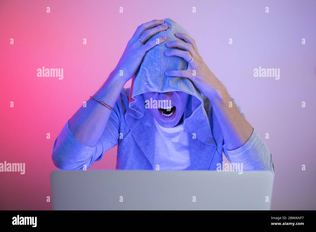 Gamer plays on a laptop. The programmer writes the code. Man on a colored background Stock Photo