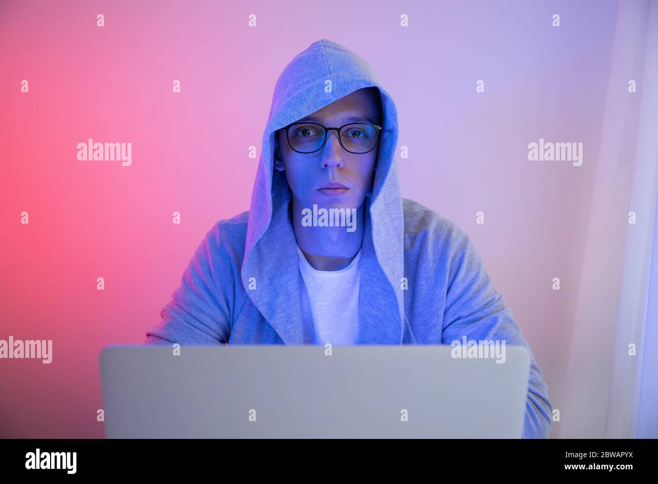 Gamer plays on a laptop. The programmer writes the code. Man on a colored background Stock Photo