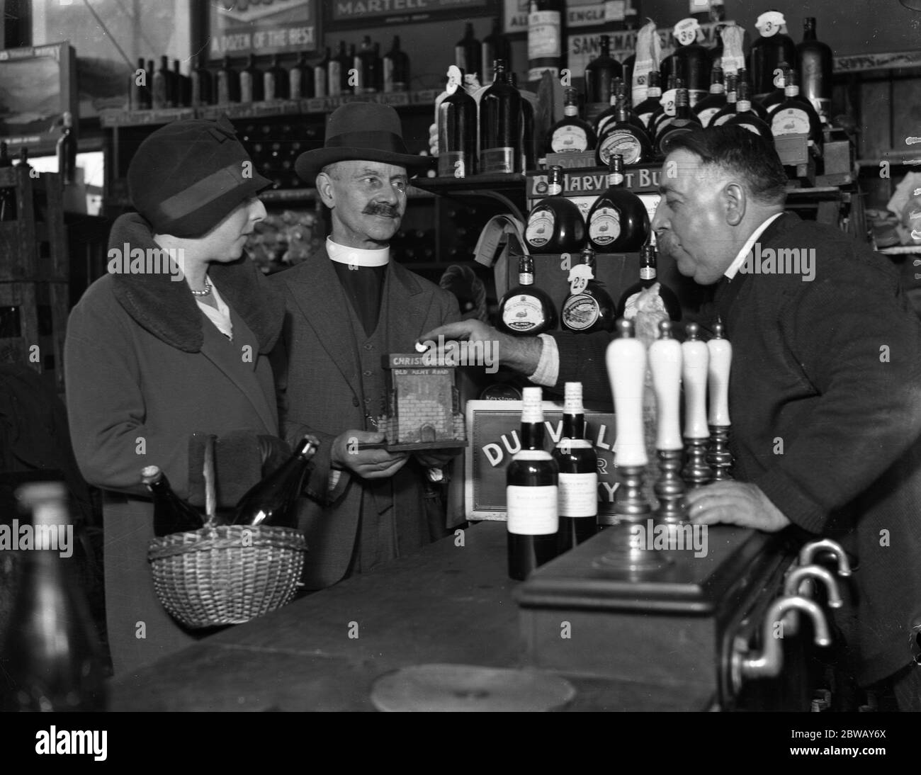 The Reverend Ernest Crellin of Christ Church , Old Kent Road , at an off - licence . He is making a tour of public houses , off - licences and shops on behalf of church funds . 29 November 1930 Stock Photo