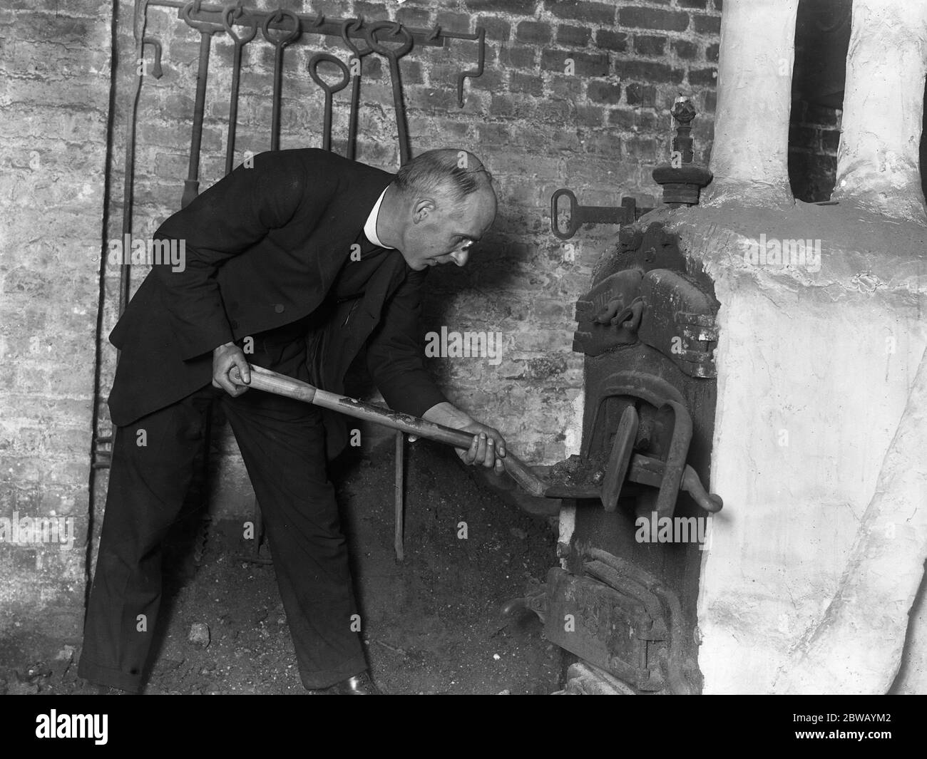 Reverend R A C Torey , Vicar of St Anne ' s Church , Hoxton , London , where each member of the congregation does something towards the work of the church . The vicar is perfoming his allotted task of stoking the furnace . 1921 Stock Photo