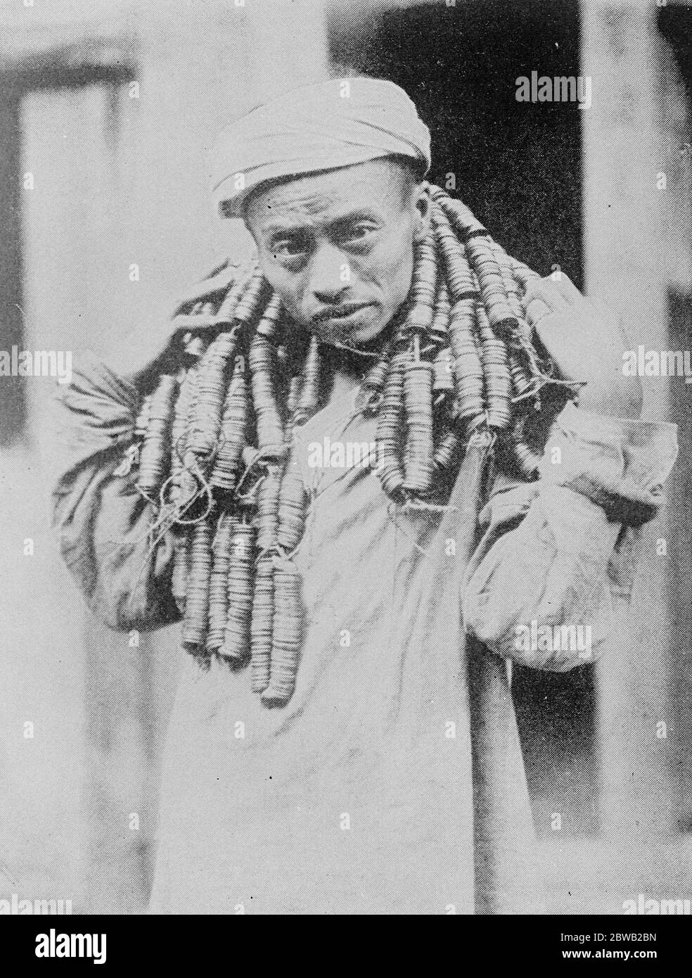 How a Chinese carries his coppers A Chinaman 's novel method of carrying 30 fen in cash . Evidently copper currency in China is a weight about the neck of people 19 May 1922 Stock Photo