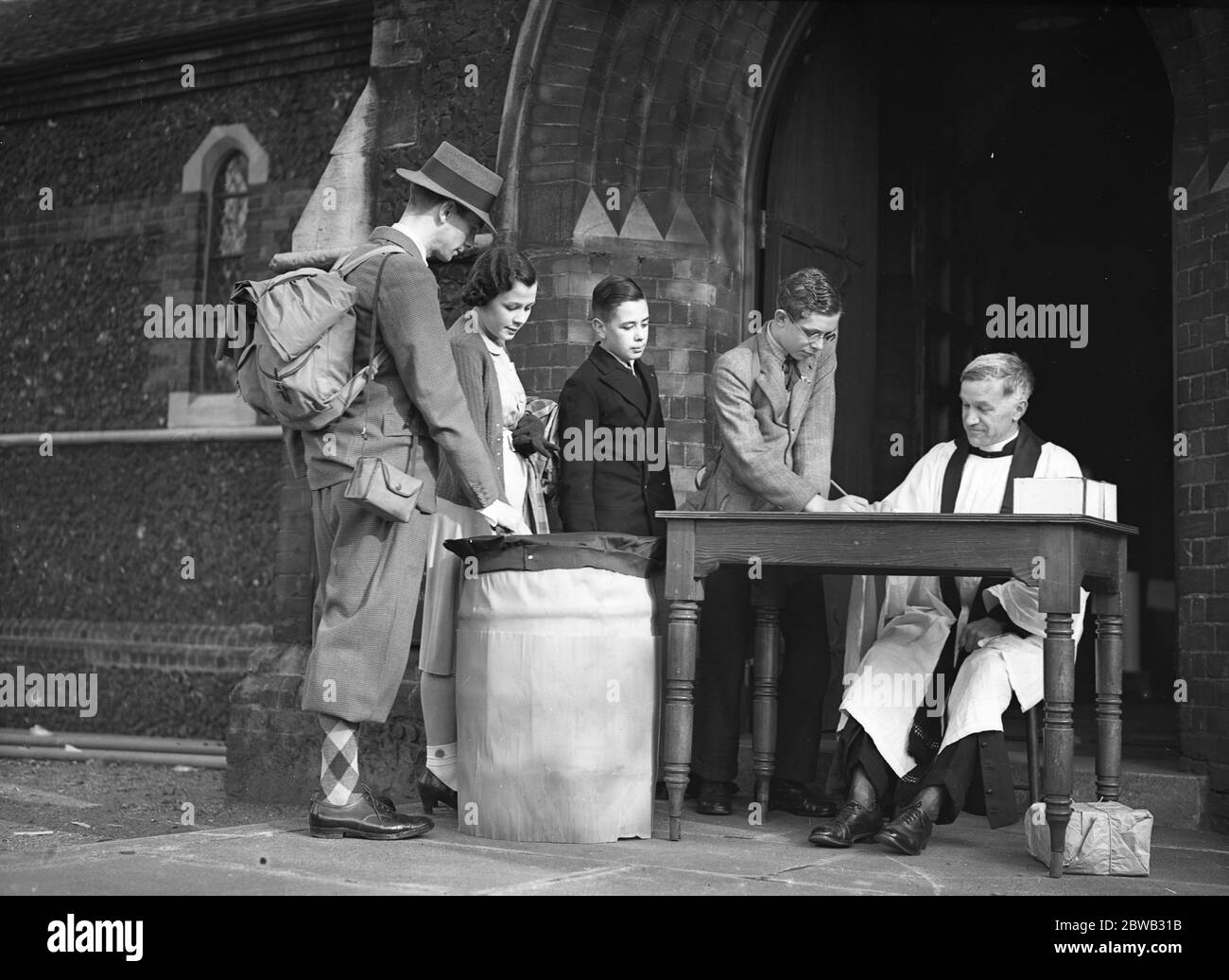 The Reverend H V Edmunds , vicar of All Saints Church , Forest Gate , sits in the porch to collect donations for the renovations to the church . 20 September 1939 Stock Photo