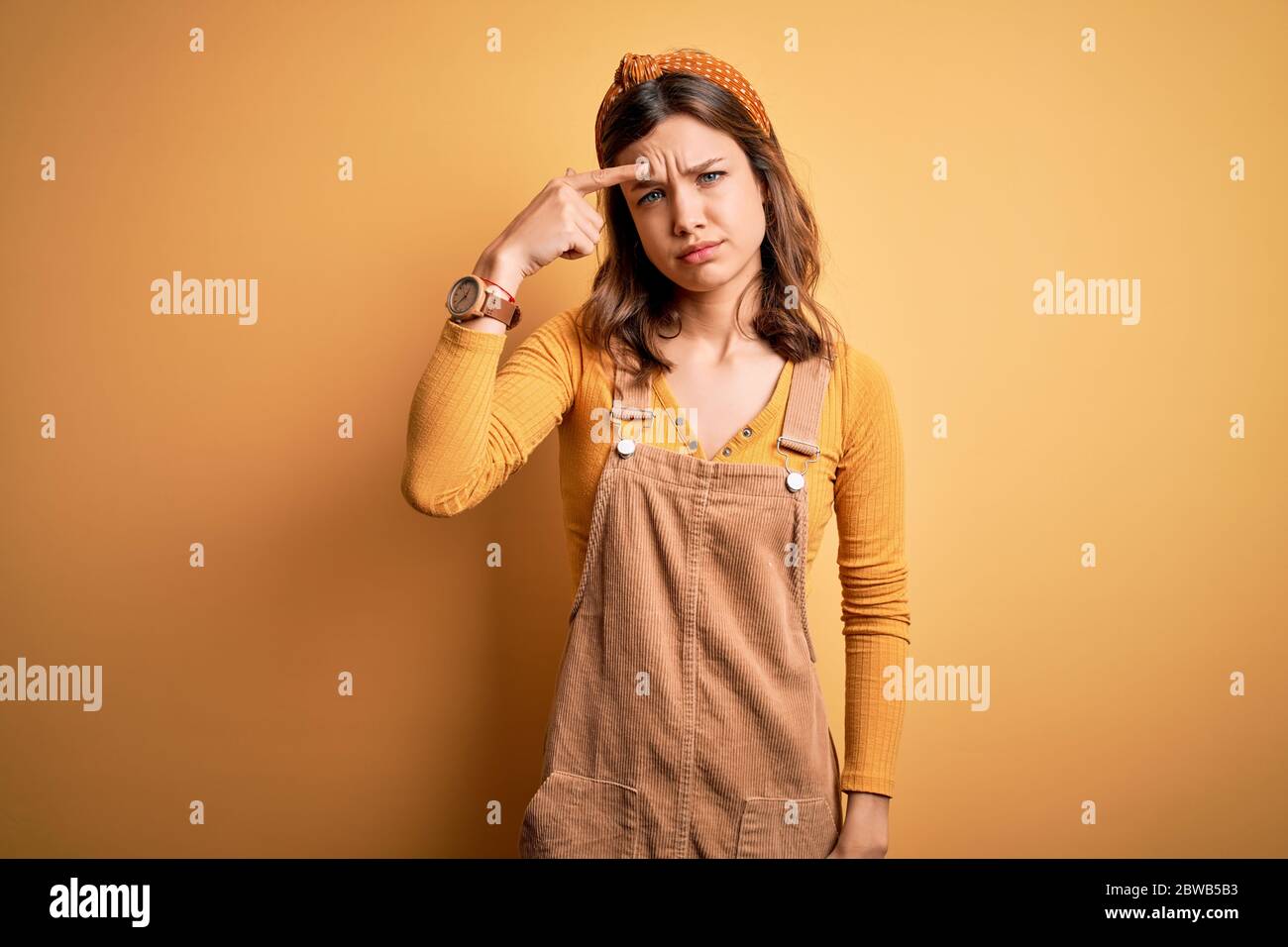 Young beautiful blonde girl wearing overall standing over yellow isolated  background pointing unhappy to pimple on forehead, ugly infection of  blackhe Stock Photo - Alamy