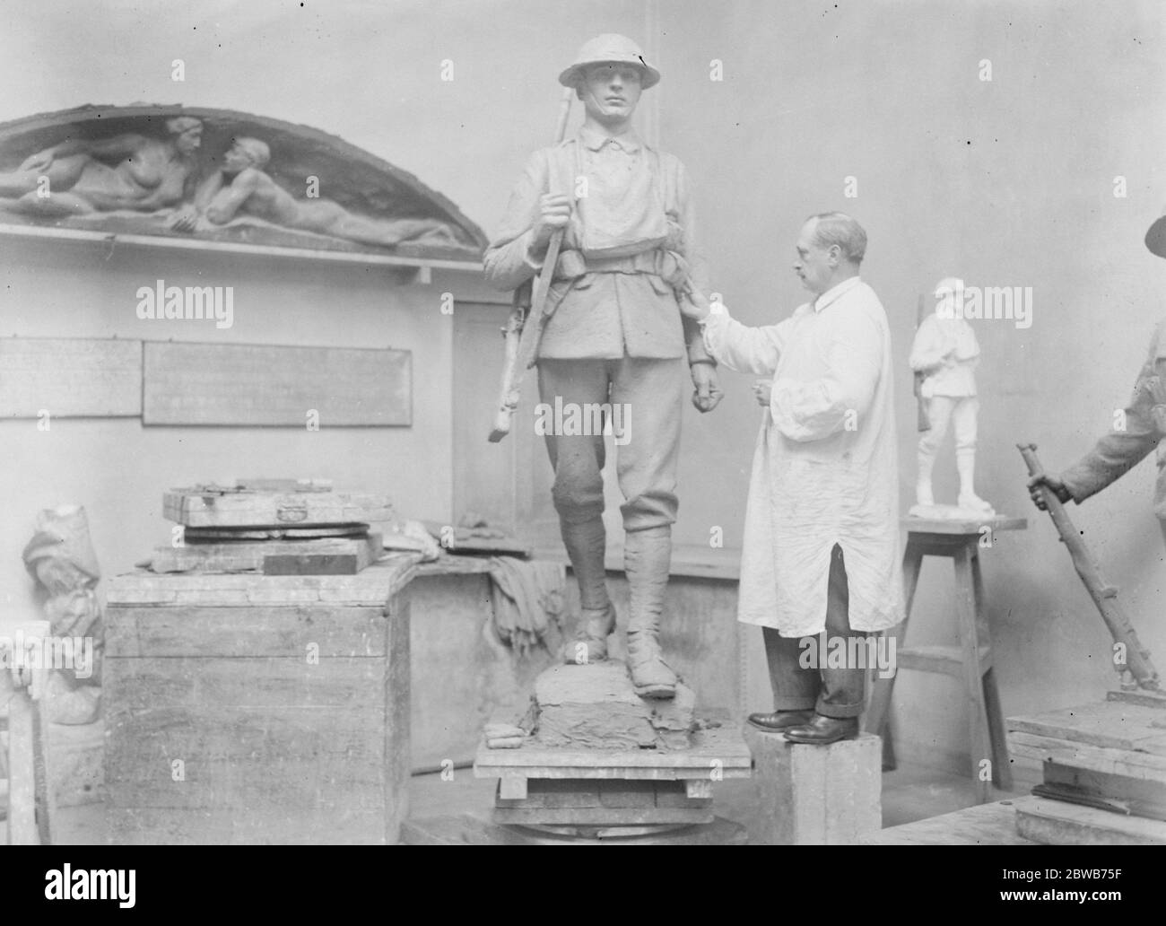 A striking memorial of architectural design for the Rifle Brigade . Mr John Tweed is engaged on the completion of a striking war memorial for the Rifle Brigade . It is of architectural design , with three imposing figures , representing different uniform periods of the regiment . Mr Tweed at work on the memorial . 8 April 1924 Stock Photo