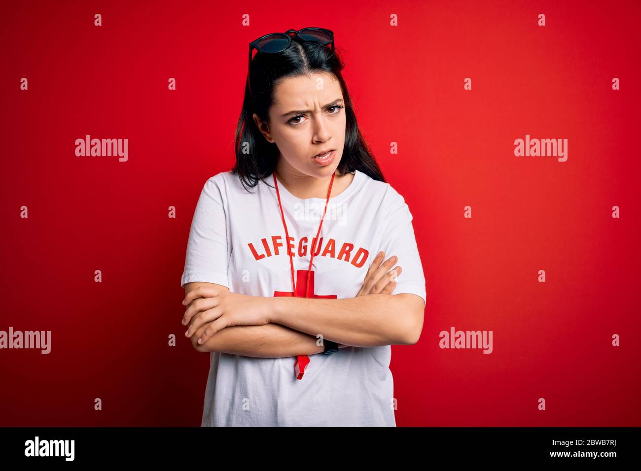 Young lifeguard woman wearing secury guard equipent over red background ...