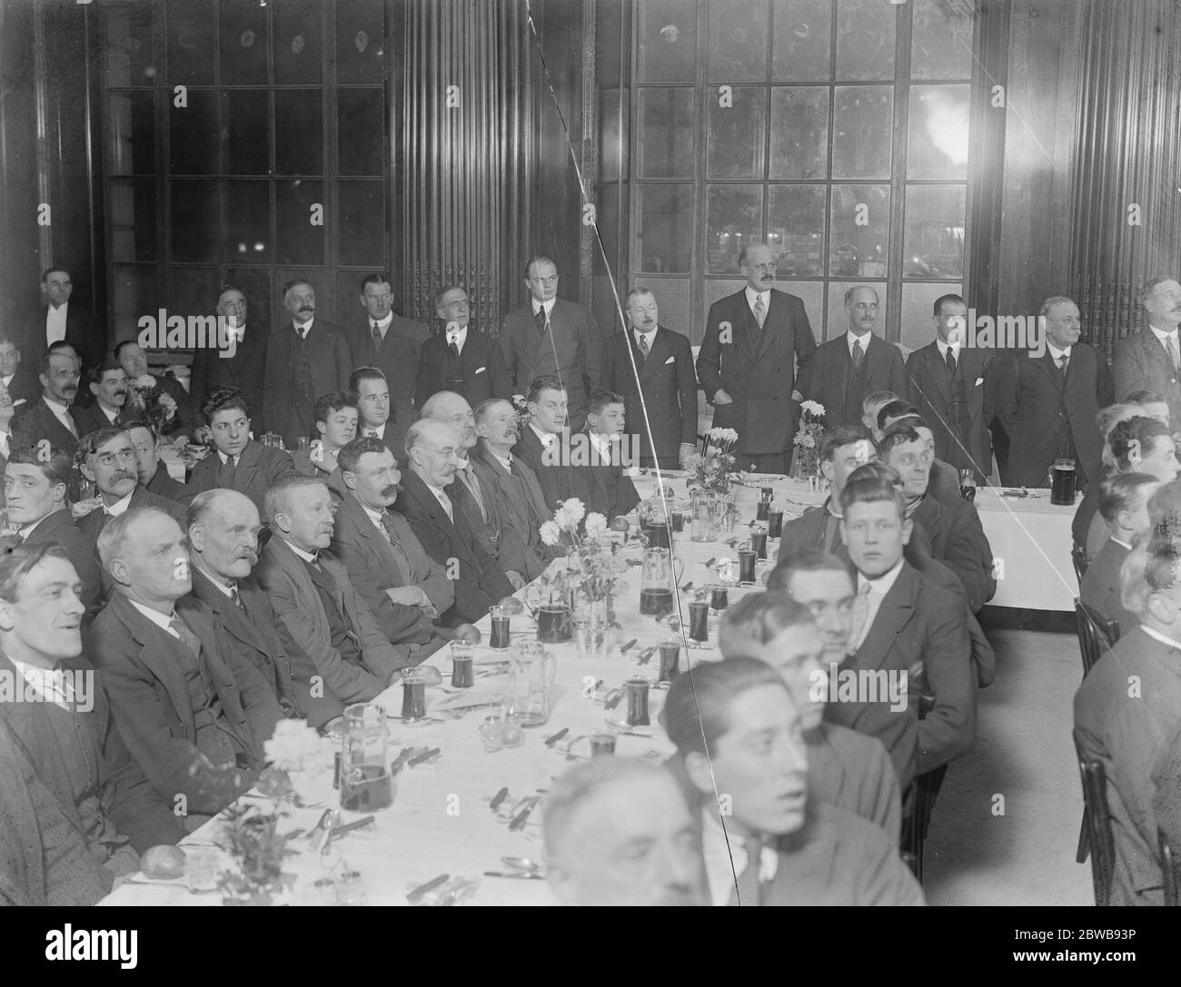 Workmen entertained to ' Christmas dinner ' in partially completed city building . Novel Banquet Given by Chairman and Directors of Hambros . Sir Eric Hambro ( Chairman ) is seen standing the third figure from right 13 December 1925 Stock Photo