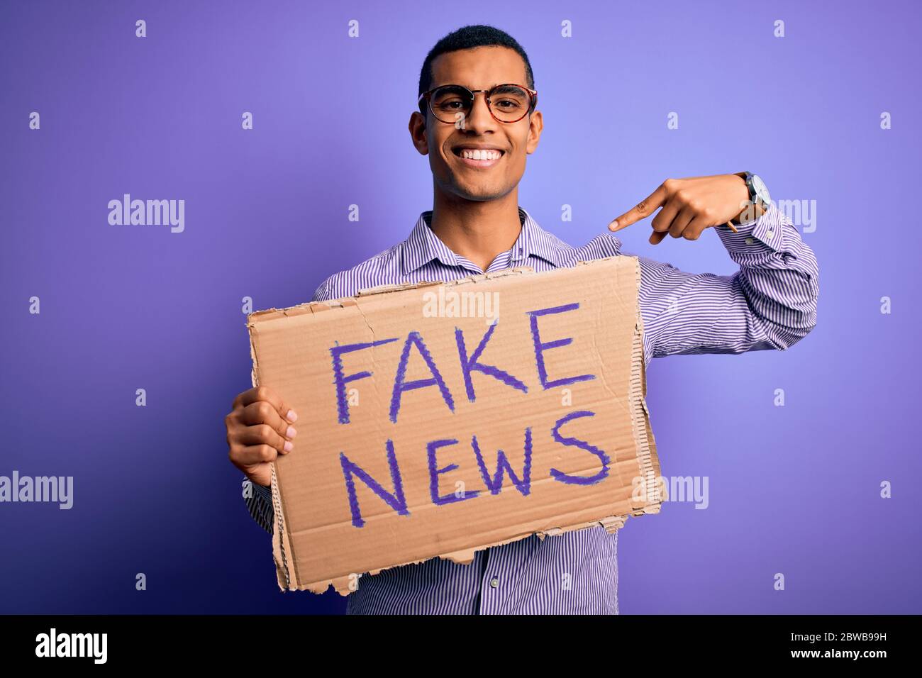 Young handsome african american man protesting holding banner with fake ...