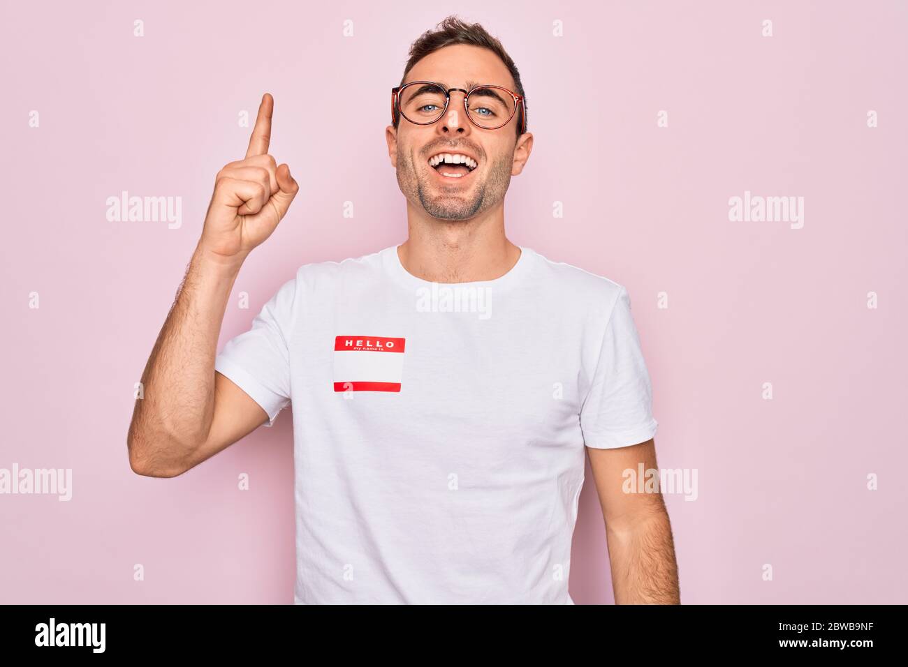 Handsome man with blue eyes wearing sticker with hello my name is ...