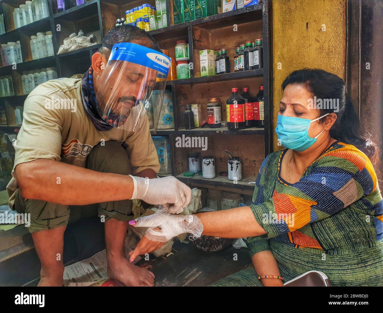Kathmandu, Nepal. 31st May, 2020. Ramesh Shakya, an Ayurvedic physician (L) wearing protective faceshield and gloves applies bandage at hand of a patient during the nationwide lockdown amid COVID-19 outbreak at his clinic in Kathmandu, capital of Nepal on May 31, 2020. The Nepal governmentÂ extends the nationwide lockdown until June 14 as the number of cases of COVID-19 are increasing in the Himalayan country. Credit: Sunil Sharma/ZUMA Wire/Alamy Live News Stock Photo