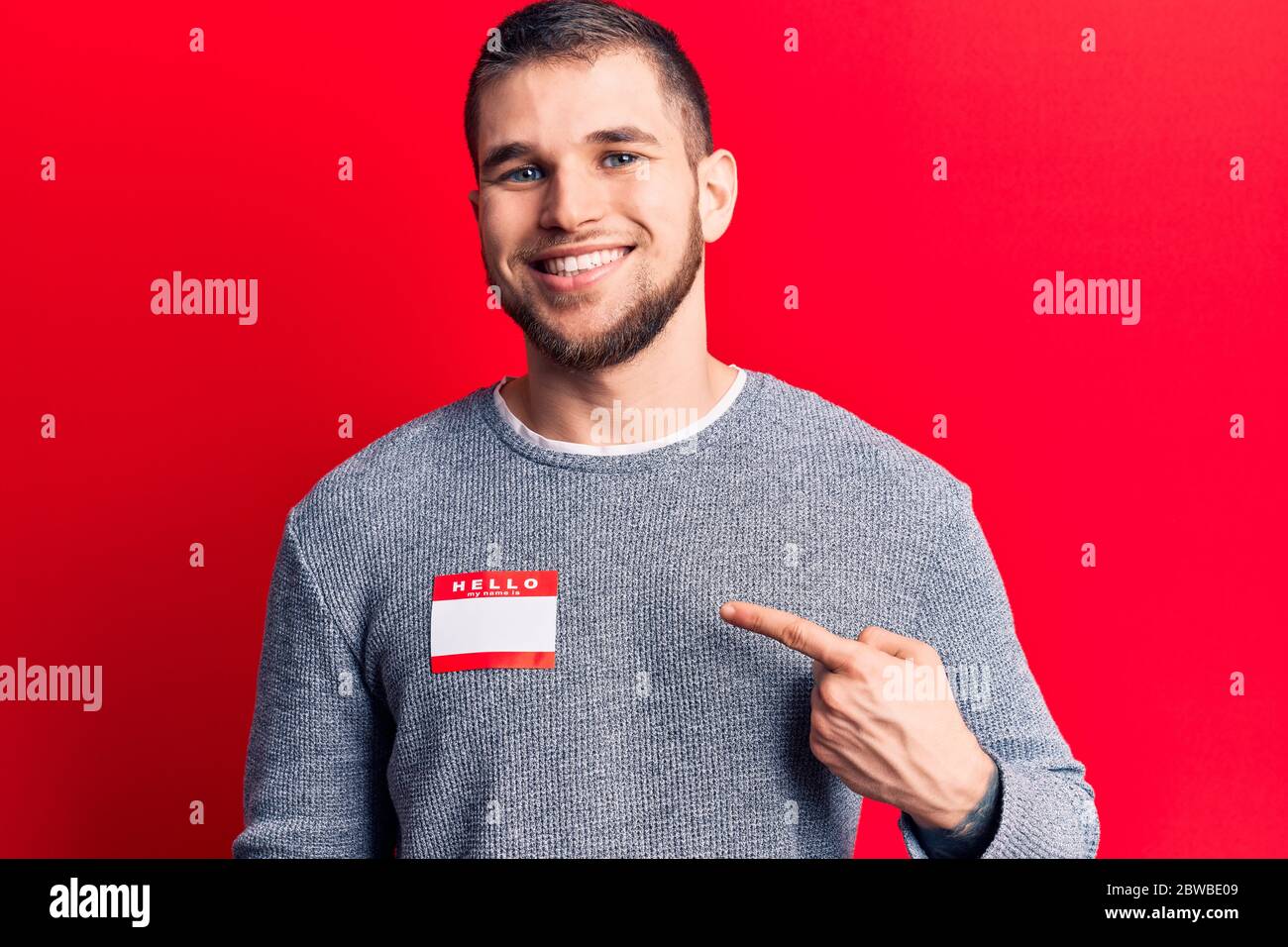 Young handsome man wearing hello my name is sticker smiling happy ...