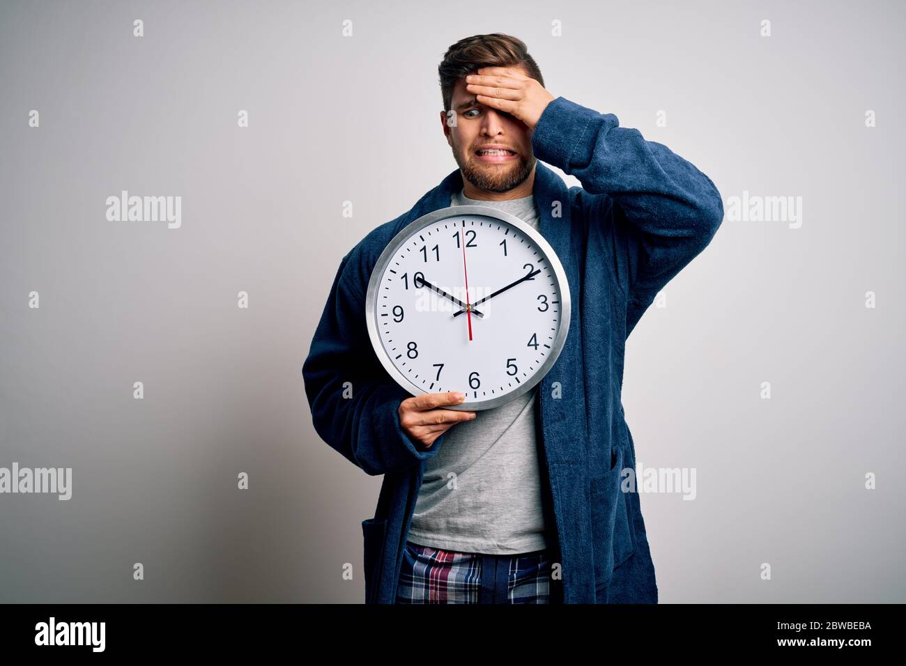 Staring At Clock Rage Young blond man with beard and blue eyes wearing pajama holding big ...
