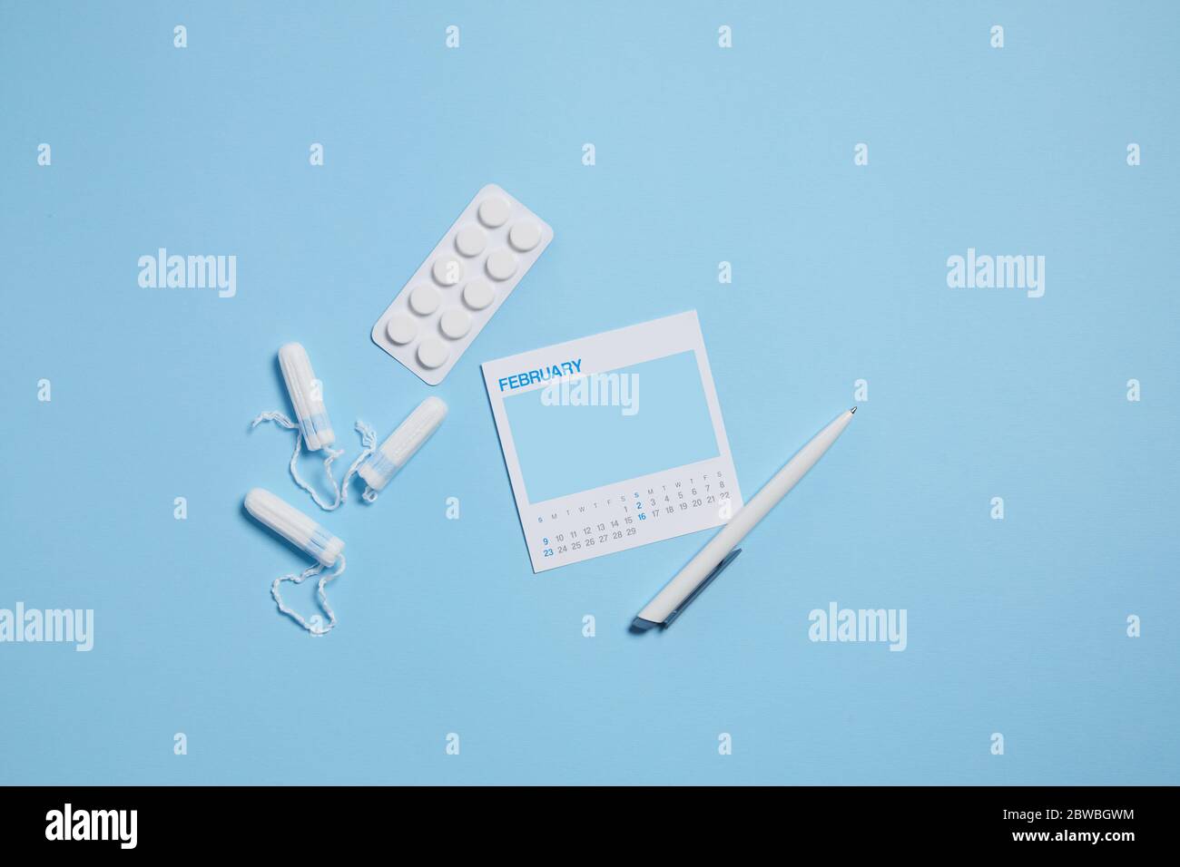 menstrual sanitary tampon, pain pills during menstruation on blue background, feminine calendar with mock up. Feminine hygiene products. top view. Stock Photo