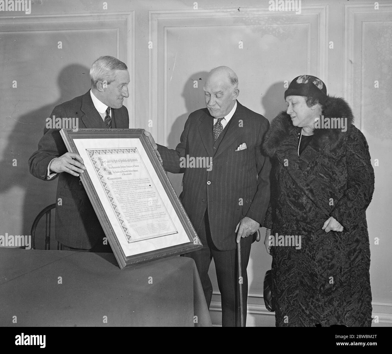 Sir Percy Bates ( left ) , of the Cunard company , presenting an illuminated address to Lord Deneigh on his retirement as commandant of the honourable artillery company , at the Cunard office , Cockspur Street . Lady Denigh is also in the picture 31 March 1933 Stock Photo