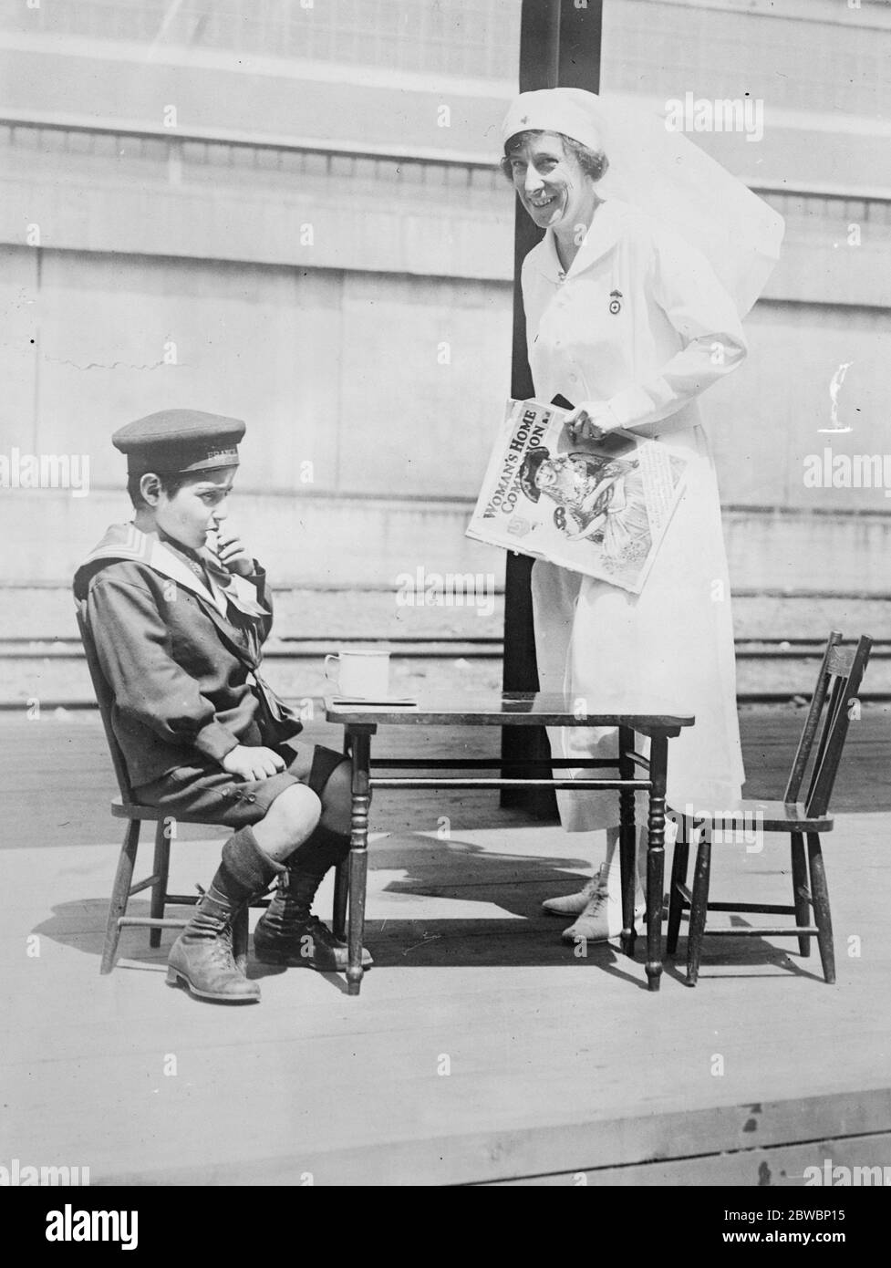 King George 's war time nurse in her favourite role . Miss Tremaine , the Canadian Army nurse , who was in attendance upon King George in France , and also at Buckingham Palace after his Majesty 's accident during the War , has devoted the greater part of her career to the care of women and children on their arrival in Canada . In the photograph she is seen with a little Armenian boy , who is eating his first meal on Canadian soil . 11 September 1923 Stock Photo