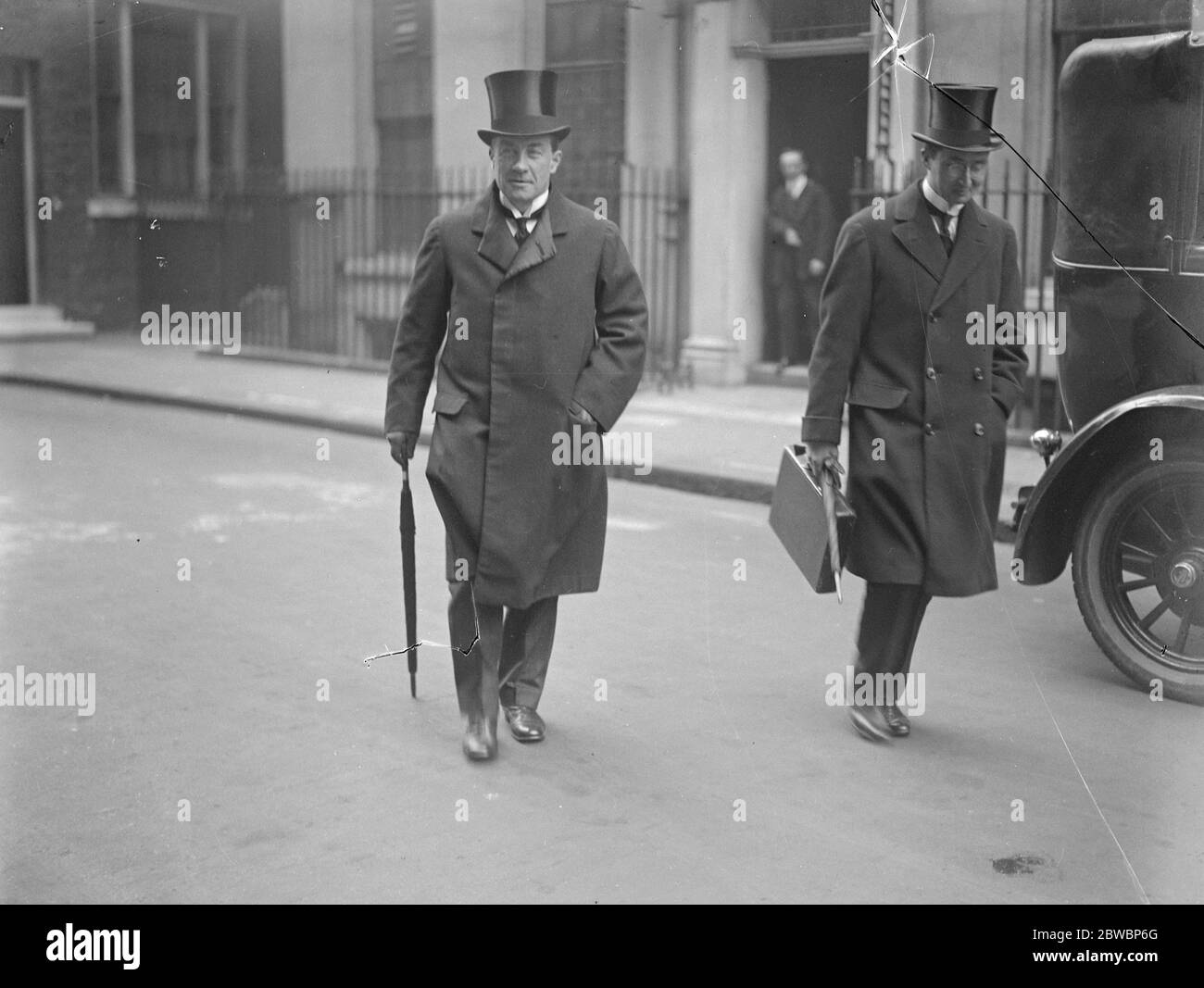 The Chancellor leaves Downing Street with the budget secrets . Mr Stanley Baldwin ( left ) Chancellor of the Exchequer , leaving Downing Street for the House of Commons to introduce the budget . His secretary is seen with hand bag containing the budget secrets . 16 April 1923 Stock Photo