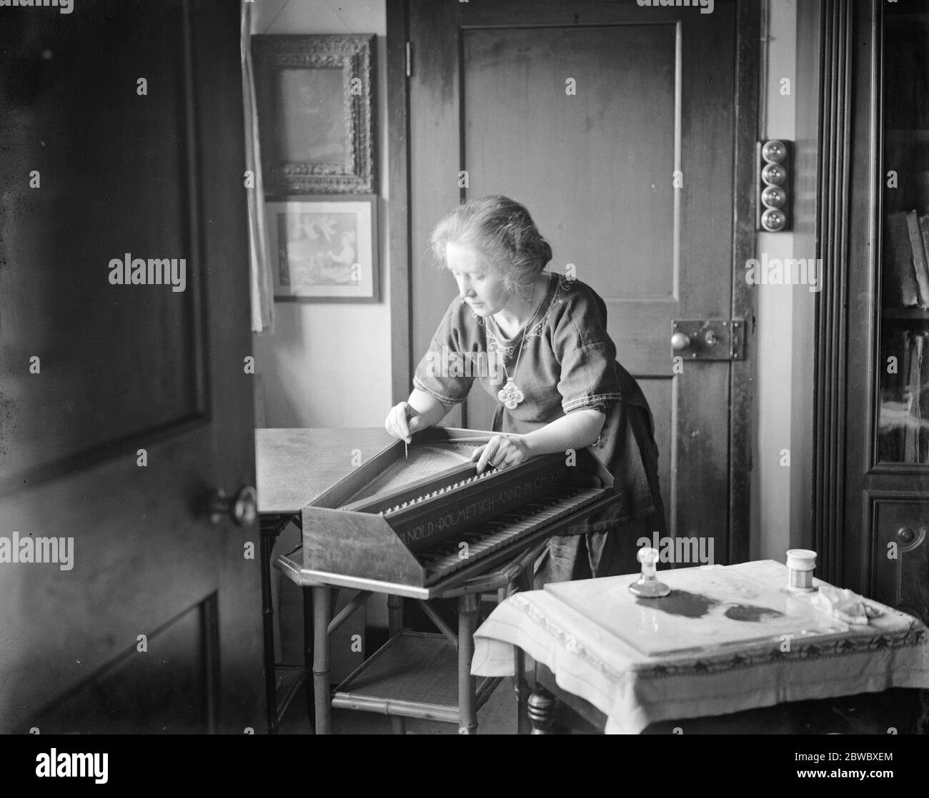 Preparing for Haslemere Festival of old chamber music . Famous family who make old time instruments . Mrs Dolmetsch , who does the exquisite floral decorations characteristic of many of these old time instruments , is here seen ornamenting a virginal . 23 January 1925 Stock Photo