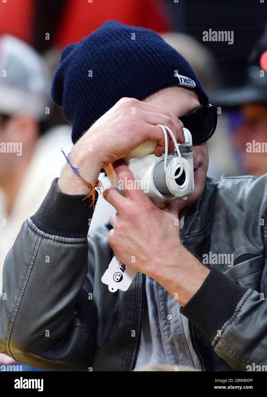 Zac Efron wearing beanie, holding camera at LA Lakers NBA game, December 2014 Stock Photo