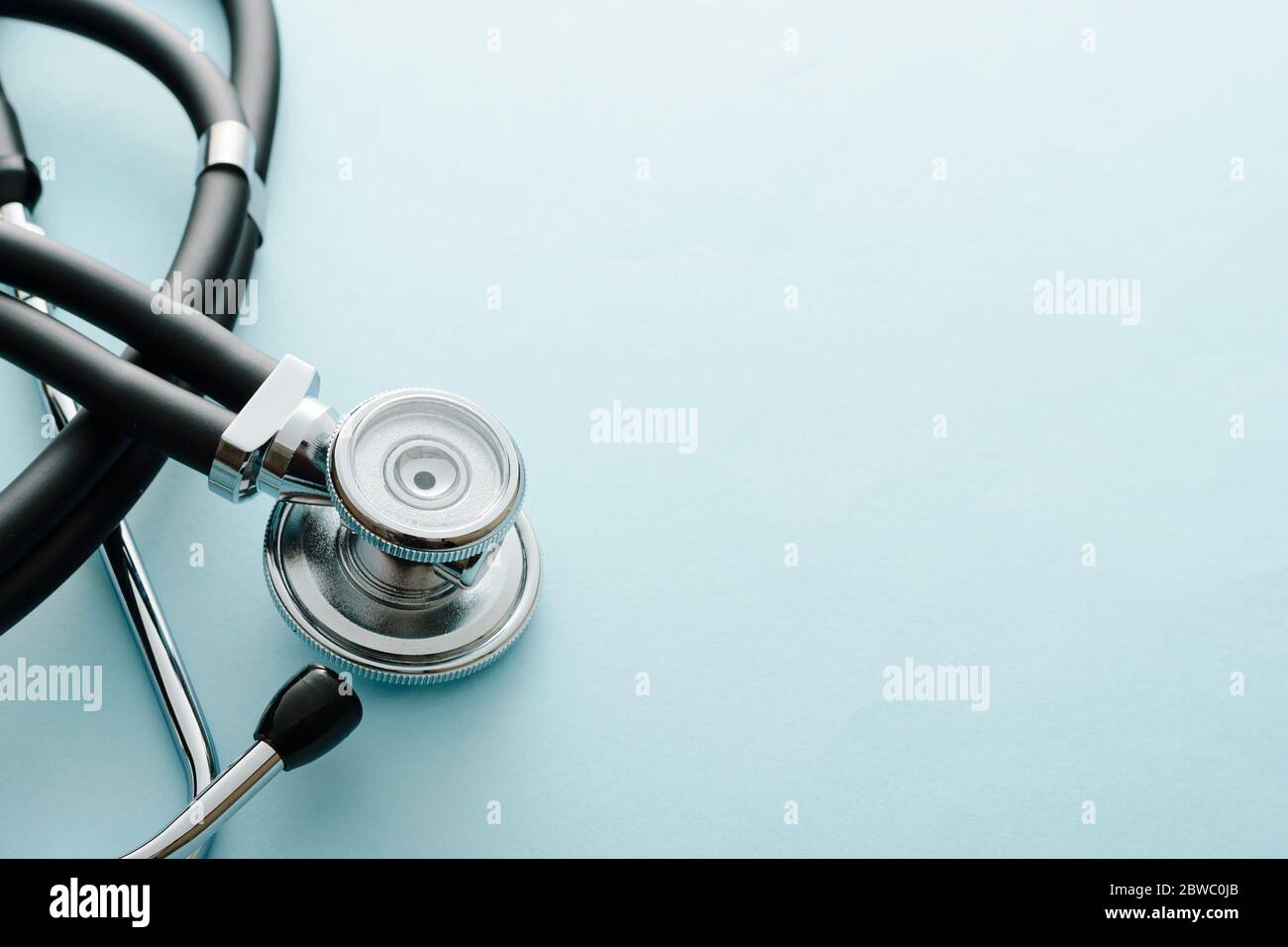 A coiled stethoscope with focus to the acoustic disc on white with copy space in a medical, healthcare or Covid-19 pandemic concept viewed from above Stock Photo