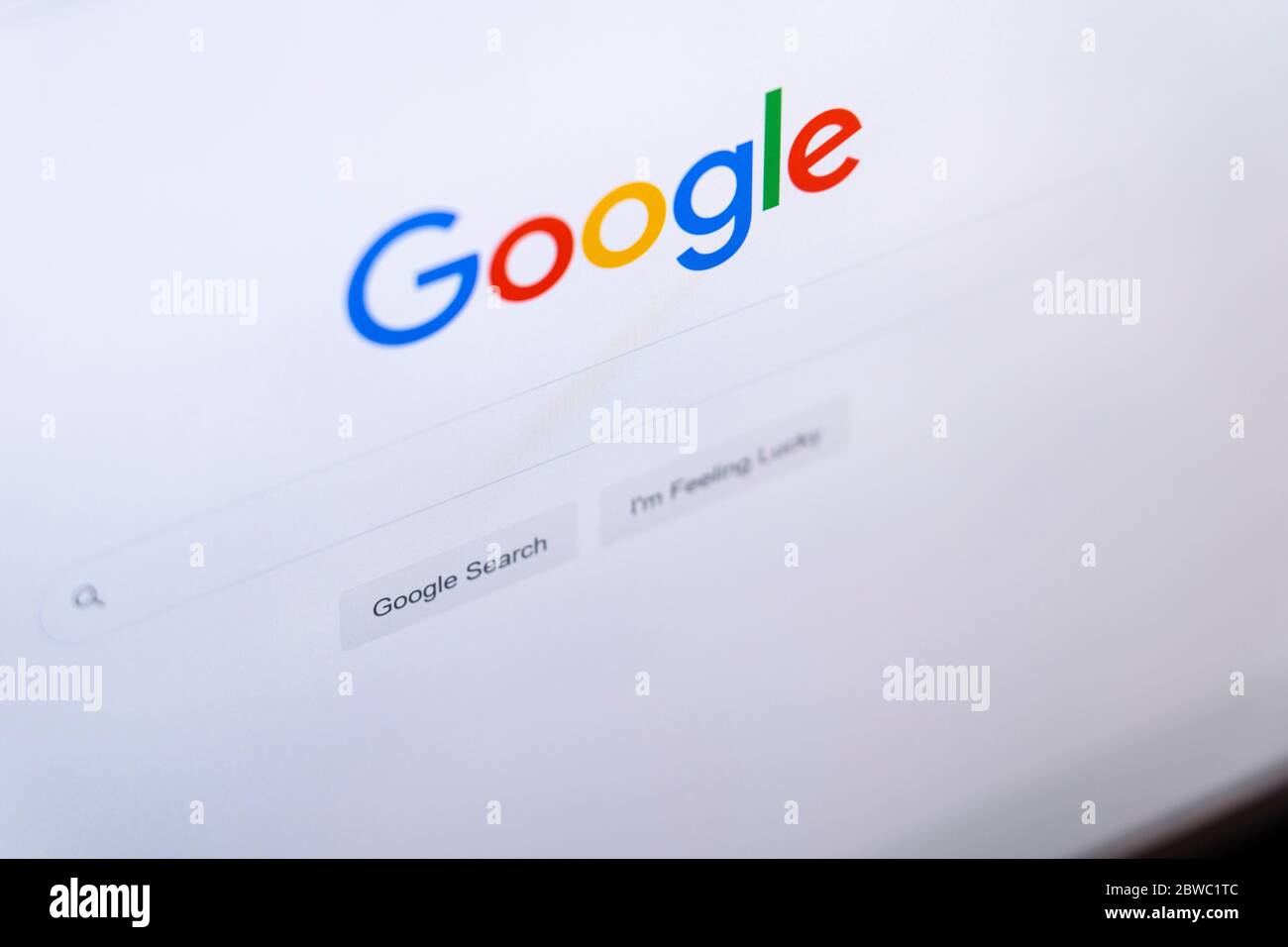 The Google homepage website with the Google logo, search bar and I'm feeling lucky button in the English language on a computer screen Stock Photo