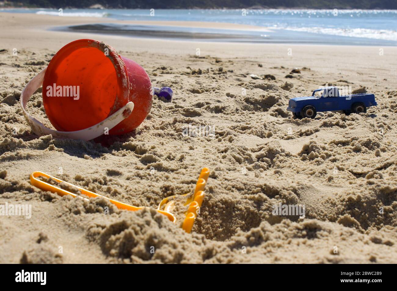 Someone has forgotten their toys on the beach, a bucket, a plastic sand rake and a police van show it. Stock Photo