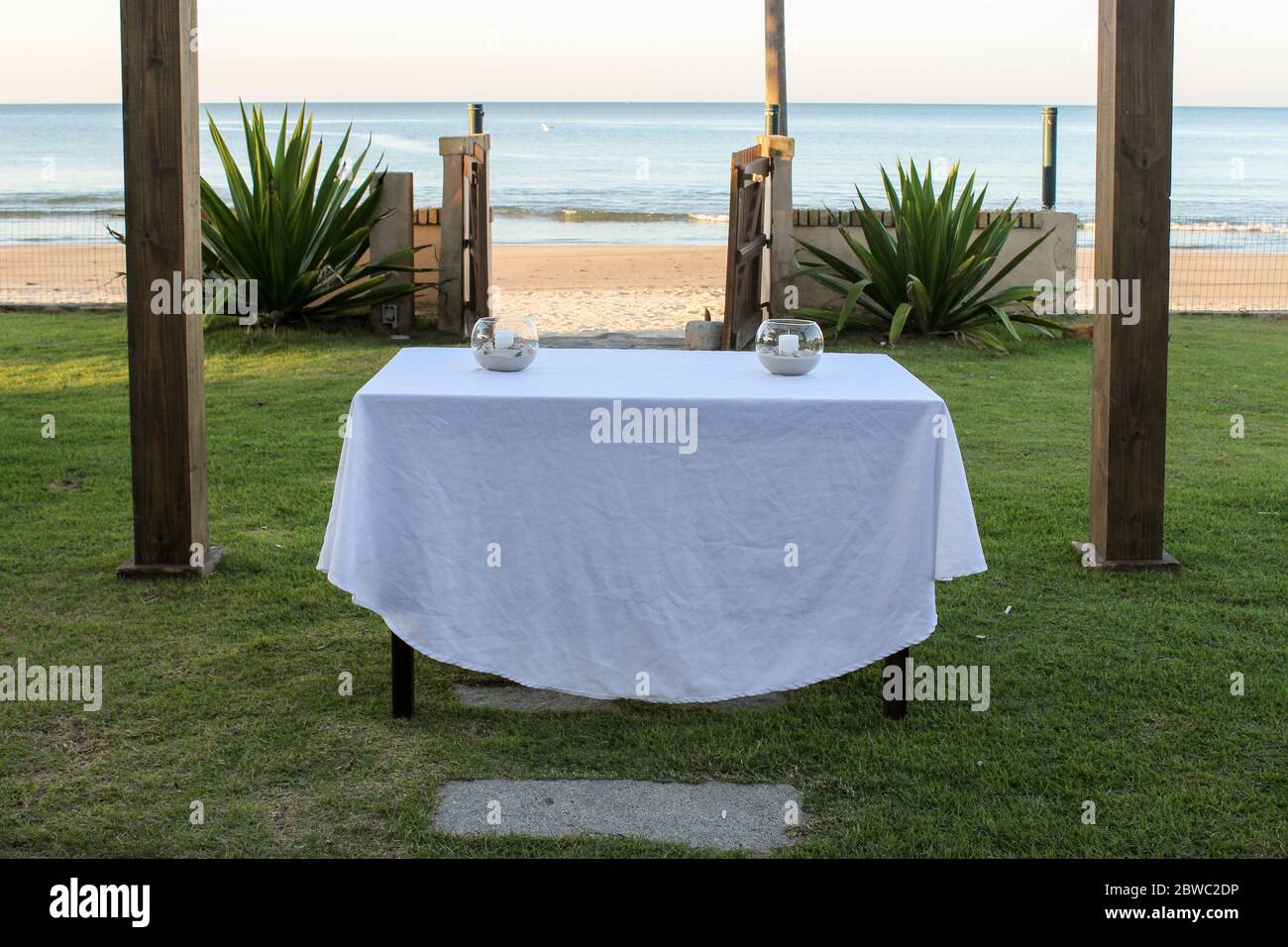 In the center of the image we have a table with two centerpieces that will function as an altar a few meters from the sandy coast and the blue sea. Stock Photo