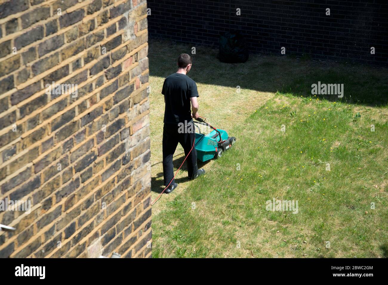 Hackney,London May 2020 during the Covid-19 (Coronavirus) pandemic. Cutting the lawn. Stock Photo