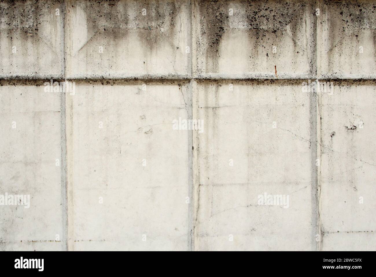 Grey old concrete wall with cracks and rectangular relief pattern. Concrete texture, space for text and layout for design. Stock Photo
