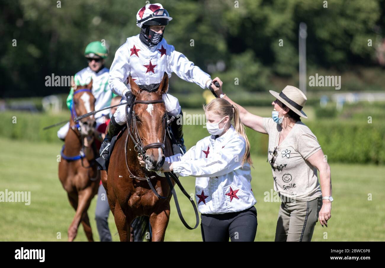 Hoppegarten, Germany. 31st May, 2020. Horse racing: Gallop, Hoppegarten Racetrack, second day of racing. Jockey Andre Best (l) clapping his hands after winning the FINUM.Private Finance AG Prize on racehorse Kellahen with trainer Sarka Schütz (r). Due to the coronavirus pandemic, the races will be held without spectators. Credit: Andreas Gora/dpa/Alamy Live News Stock Photo