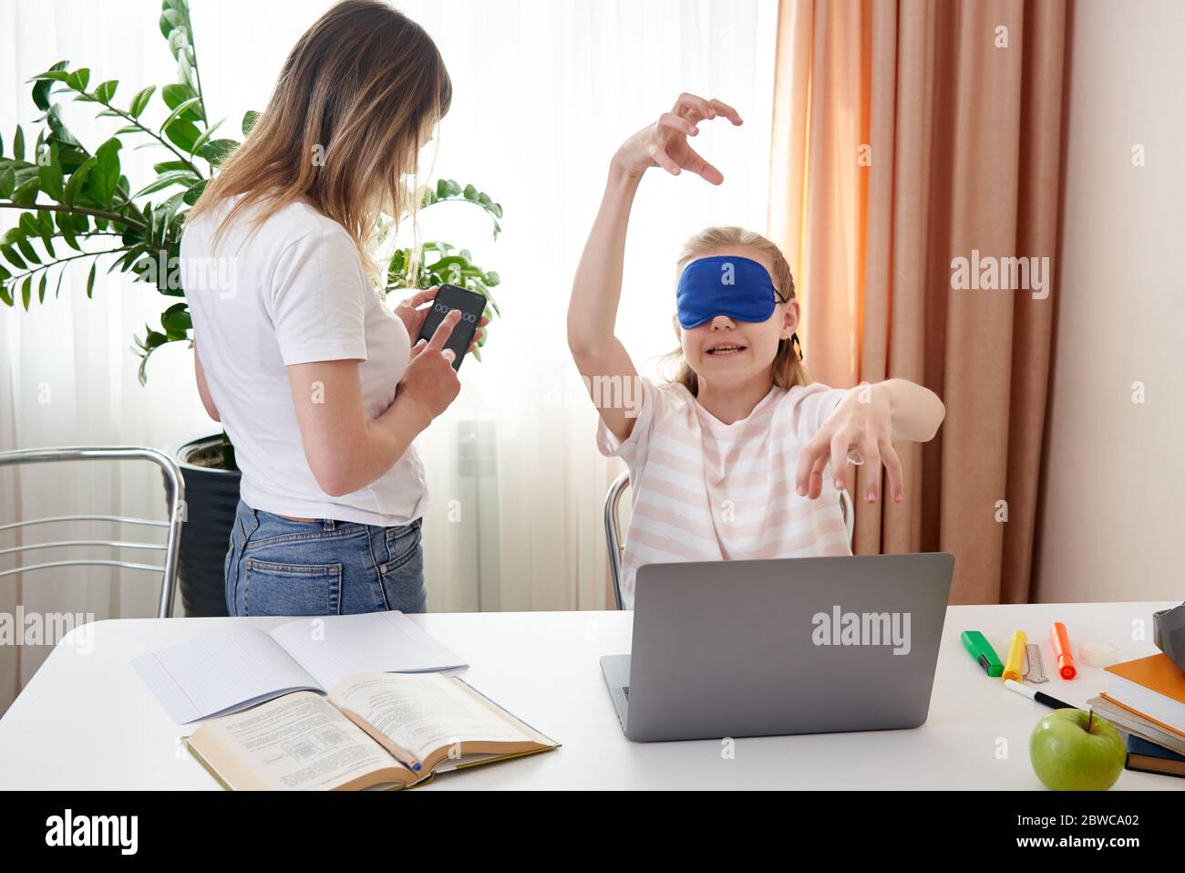 Mother helping teenage daughter to learn touch typing on keyboard, girl