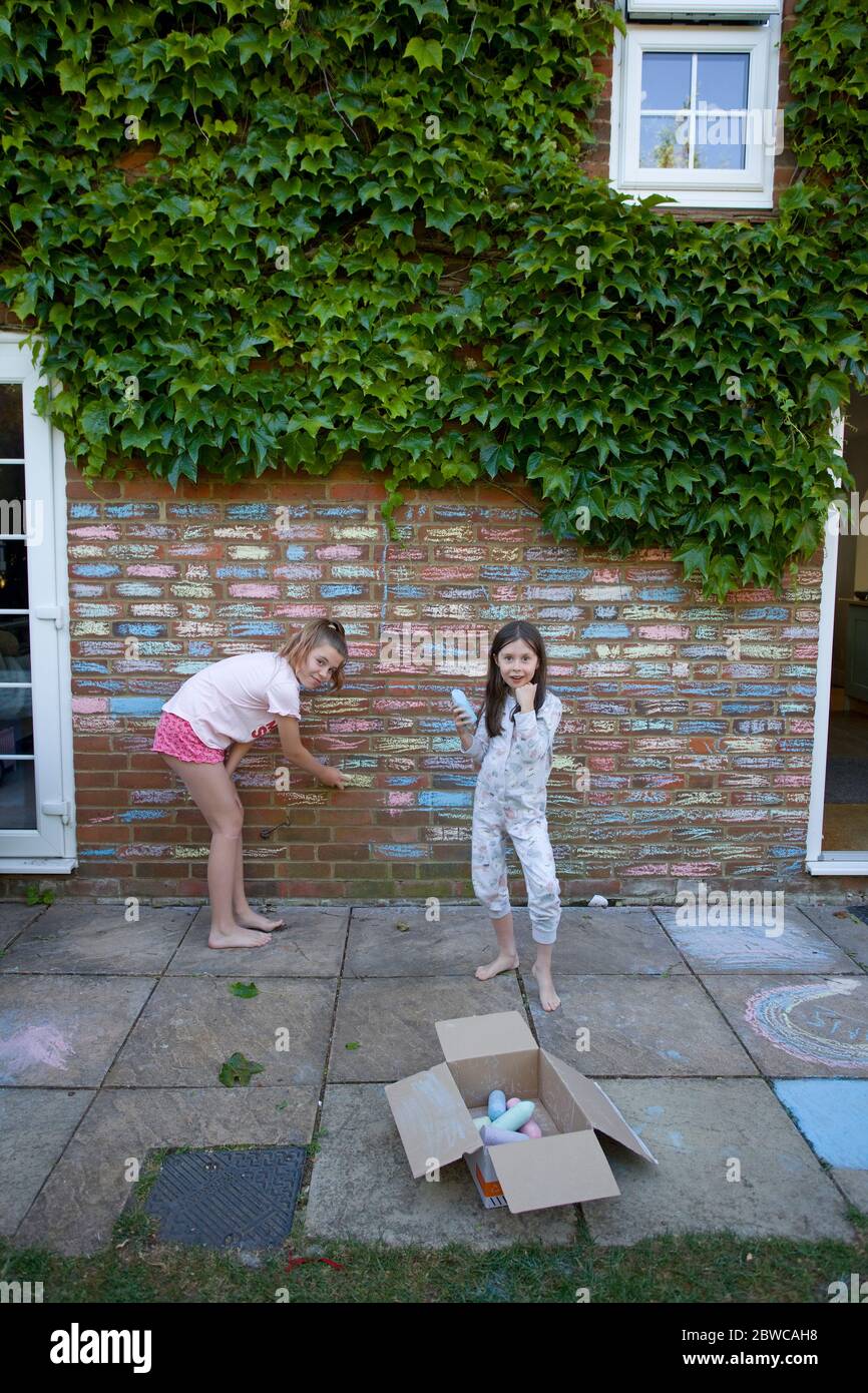 Young girls colouring in house bricks with chalks, Uk Stock Photo