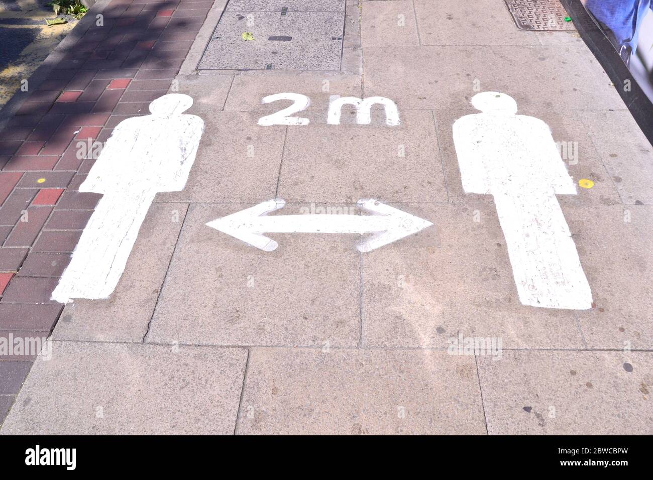 Markings on the pavement in central Manchester, England, United Kingdom remind pedestrians to keep 2 metres apart during the Coronavirus pandemic. In May 2020 uk Government Ministers are reported to be considering whether to relax the two-metre rule for social distancing. Stock Photo