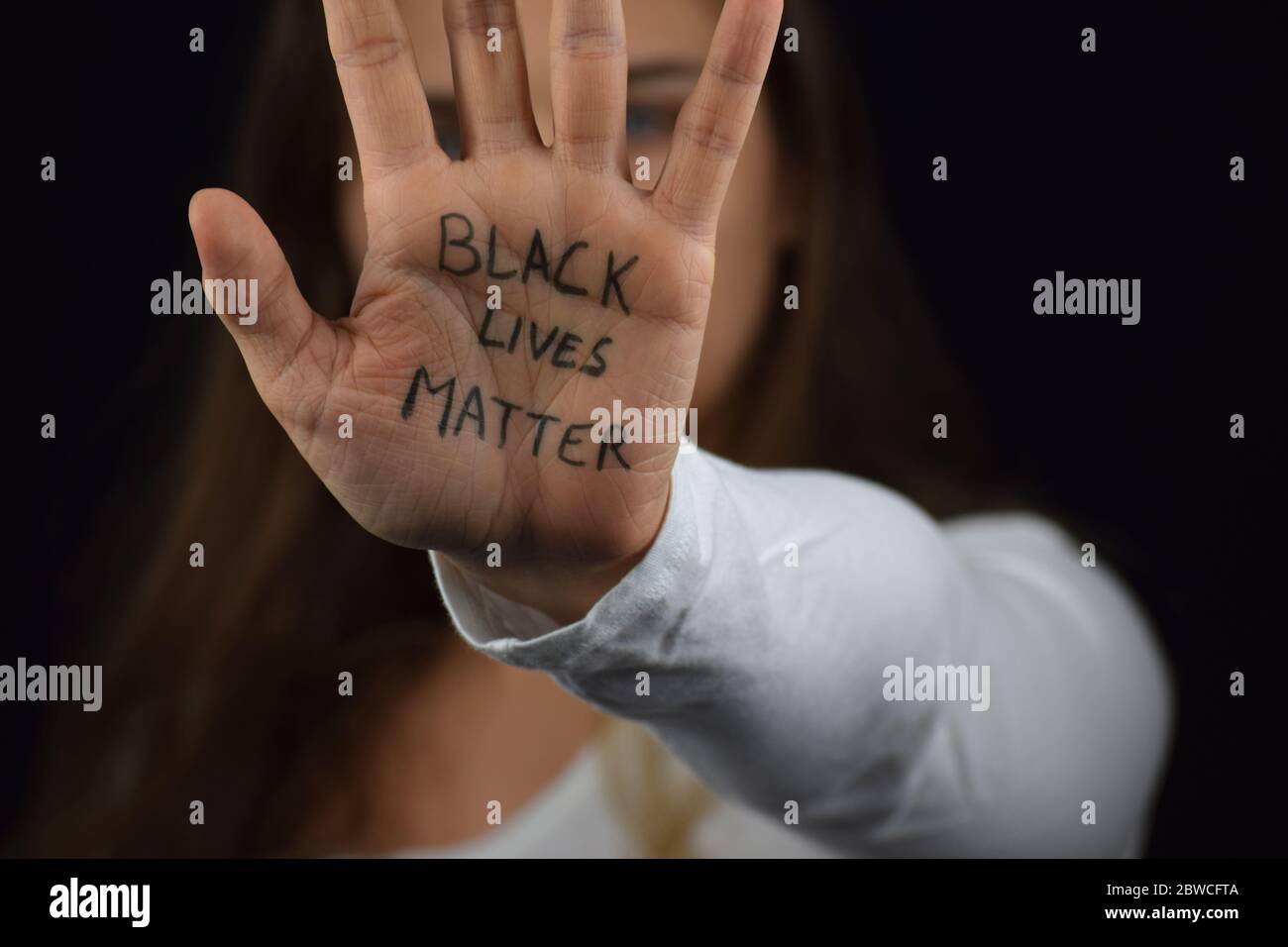 Caucasien woman holding her palm with text Black Lives Matter in support of peaceful protests against police brutality and racism Stock Photo