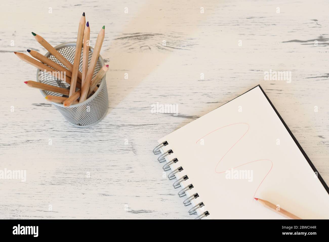Pencil pot with color pencils and a notebook with a red trace Stock Photo