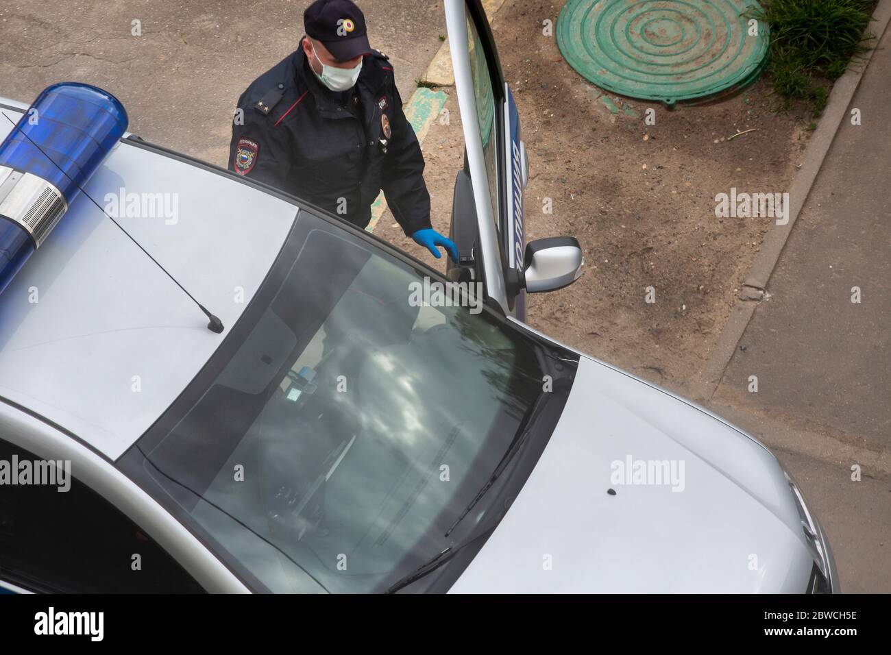 Moscow, Russia. 25th of May, 2020 A police officer wearing a protective mask and gloves gets into a patrol car on a street in Moscow during the novel coronavirus COVID-19 epidemic in Russia Stock Photo