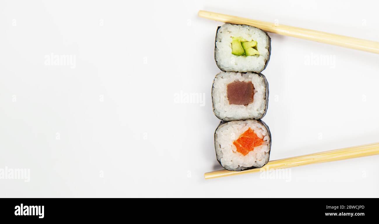 Sushi roll with chopsticks, with cucumber kappa maki roll. Japanese  kitchen. Various sushi and rolls with fish cheese and with chuka salad in  chopsticks isolated on a white background Stock Photo -