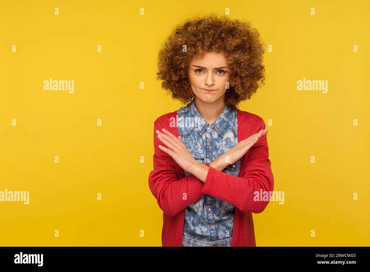 Stop, banned access. Portrait of young curly-haired woman crossing hands, warning with x sign, rejecting troubles with definitive no, body language. i Stock Photo