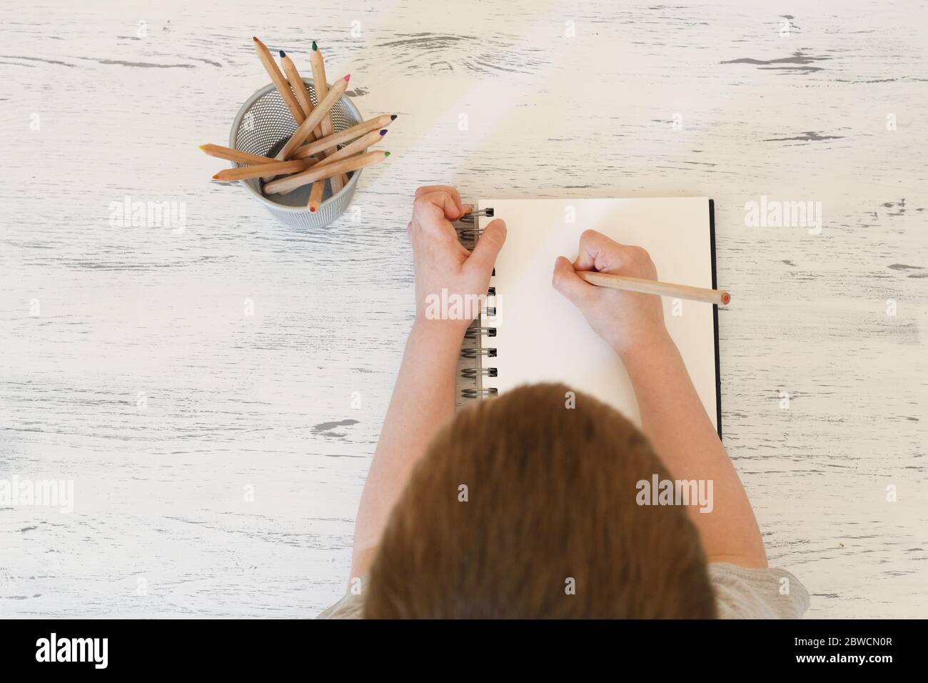 Kid prepared to make a draw over  a white notebook page. Stock Photo