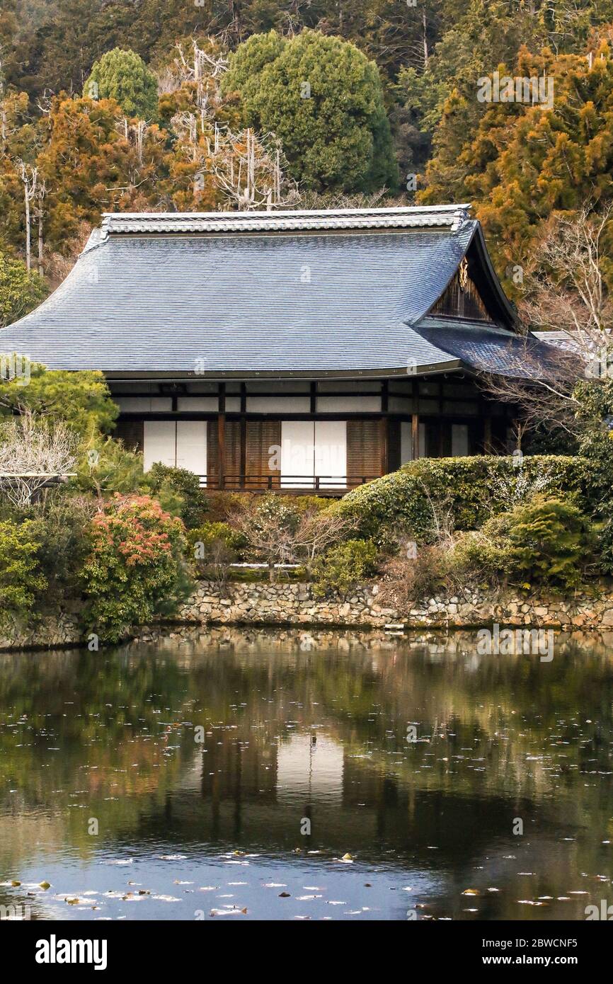 Traditional Japanese architecture, old wooden house surrounded by nature in autumn in Japanese garden with pond Stock Photo