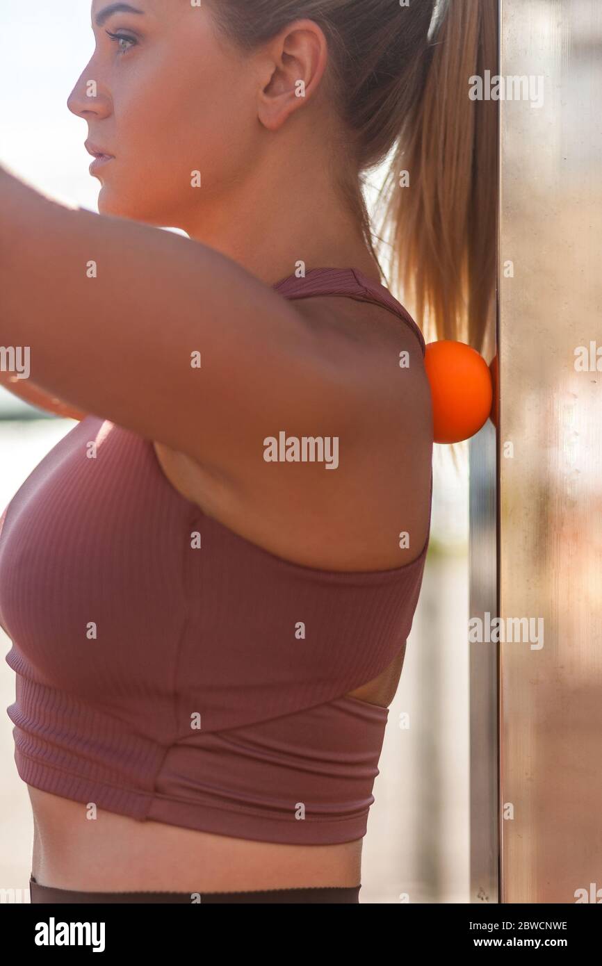 Closeup young woman shoulders in tight top leaning on small ball against  wall to fix back ache, massaging stiff muscles and sore neck, exercise to  rel Stock Photo - Alamy