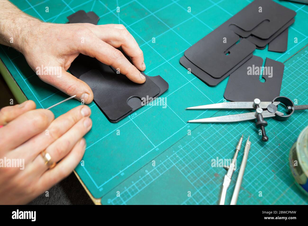 Leather Craftsman working with leather. Making a wallet. Stock Photo