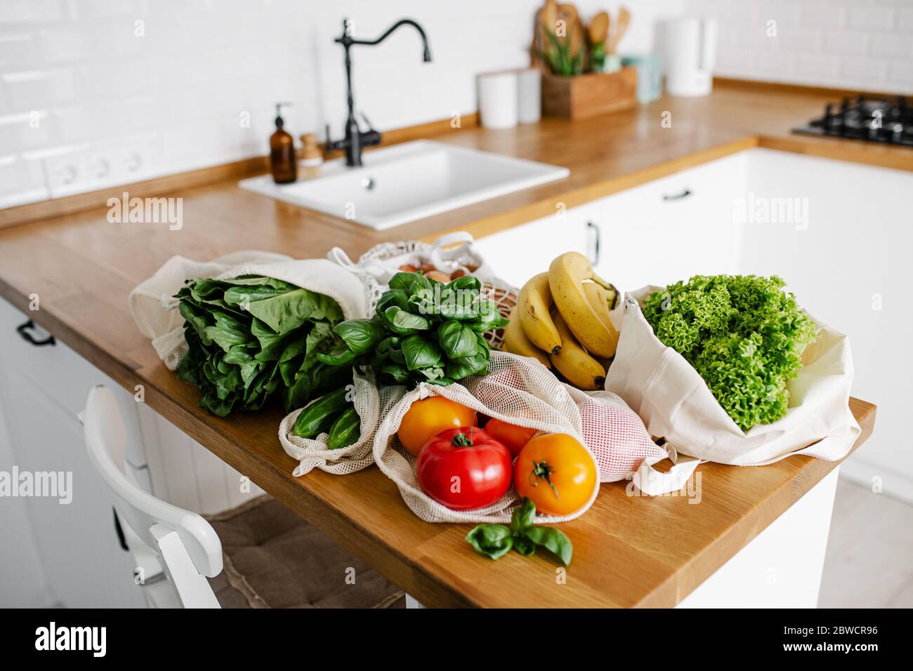 Fresh vegetables and fruits in eco cotton reusable bags on wooden table ...