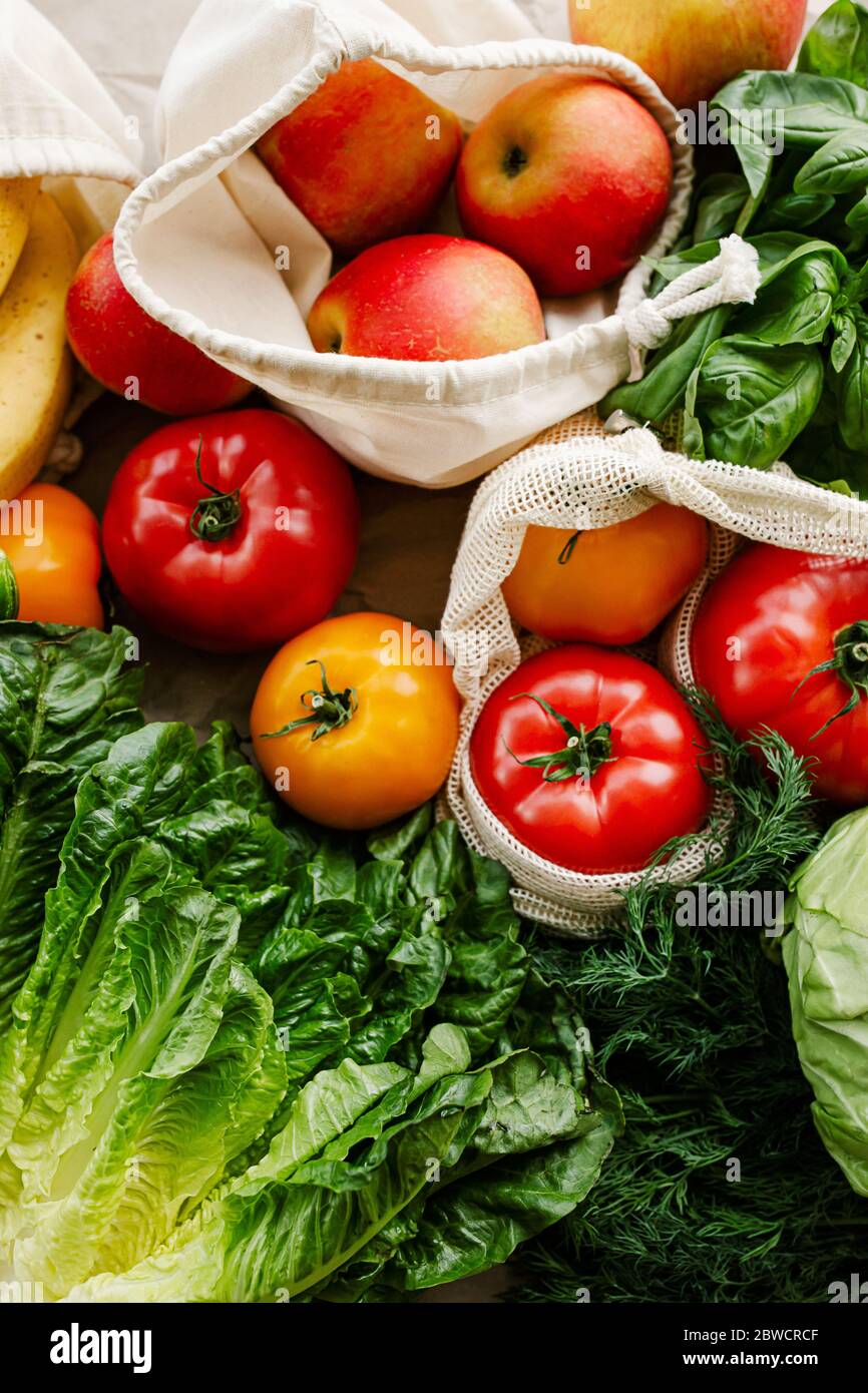 Fresh vegetables and fruits in eco cotton reusable bags on table in the kitchen. zero waste shopping concept. Sustainable living Stock Photo