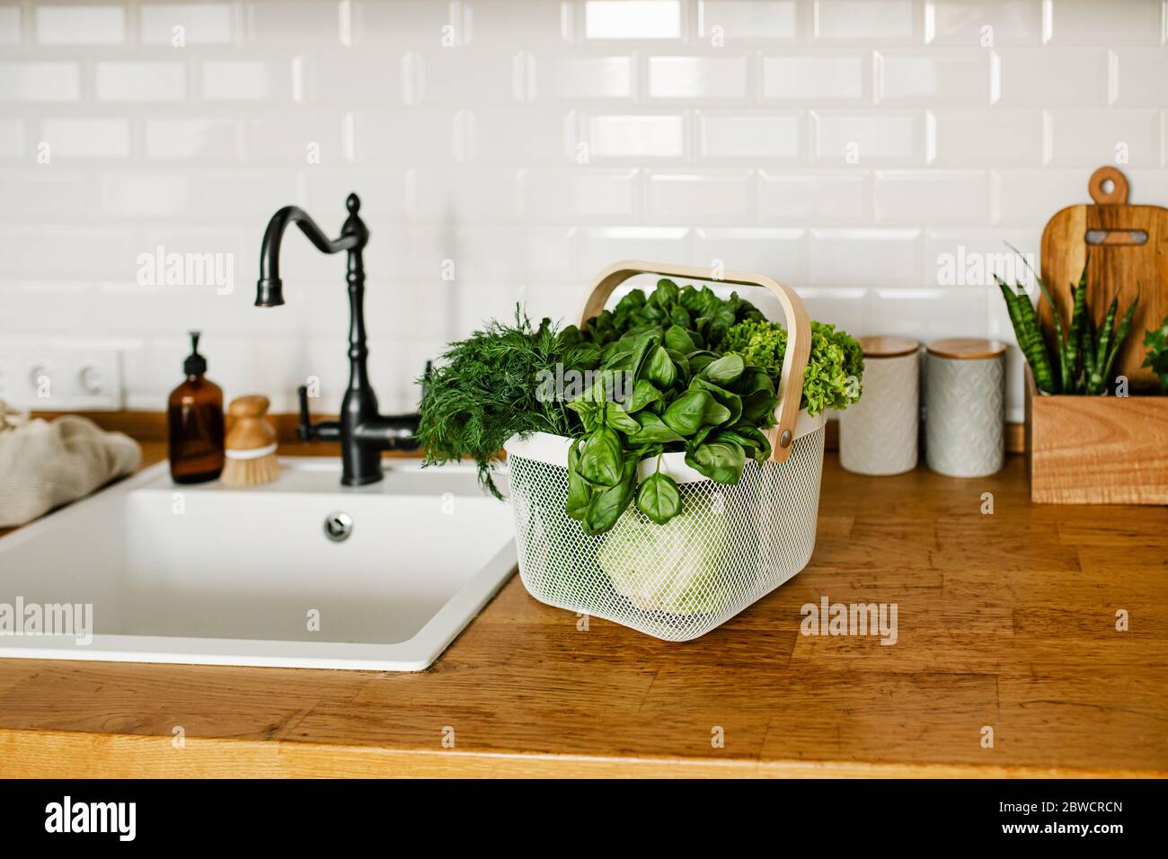 Fresh salads and herbs in metal basket on table in the kitchen. zero waste shopping concept. Sustainable living Stock Photo