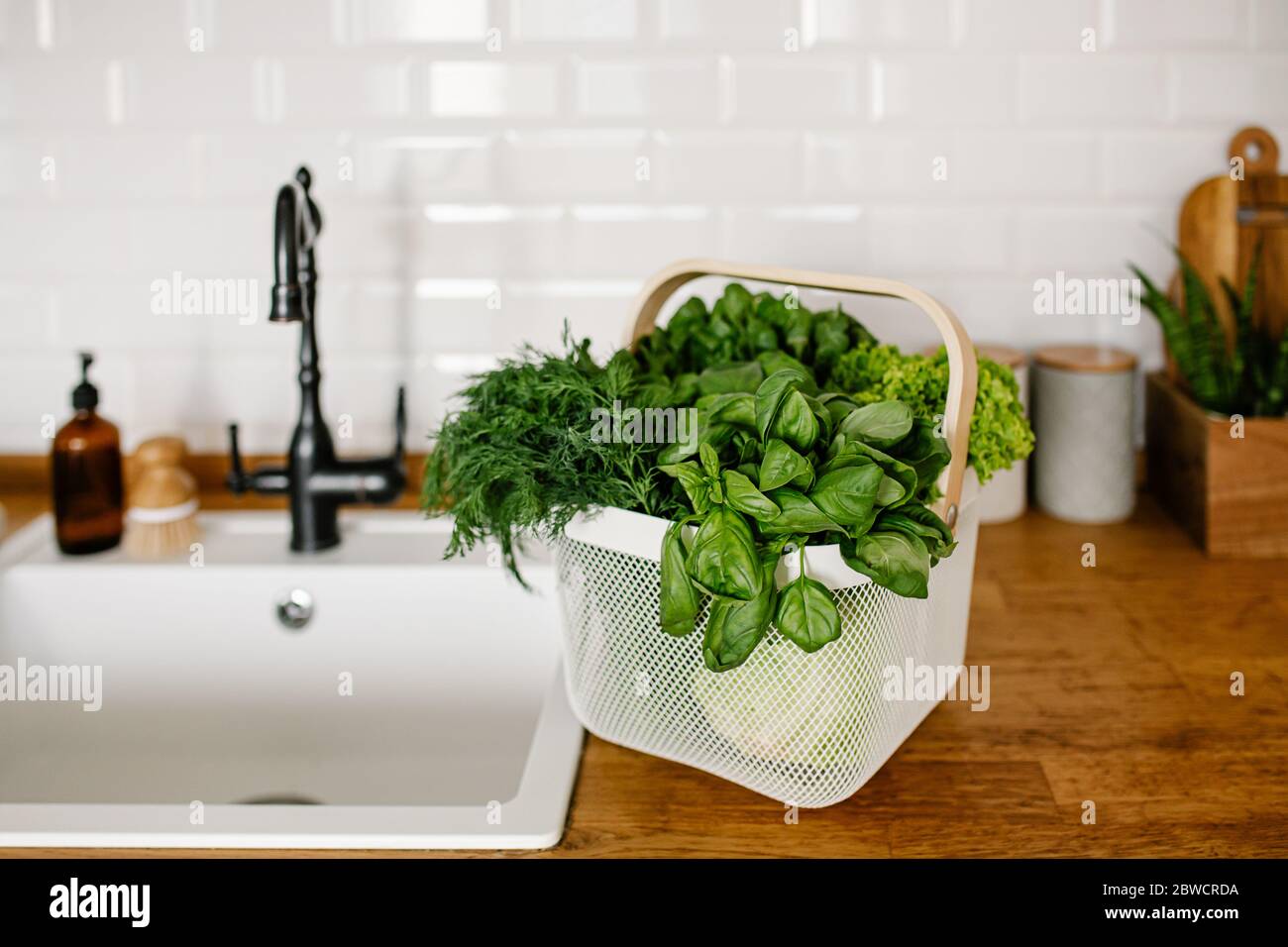 Fresh salads and herbs in metal basket on table in the kitchen. zero waste shopping concept. Sustainable living Stock Photo