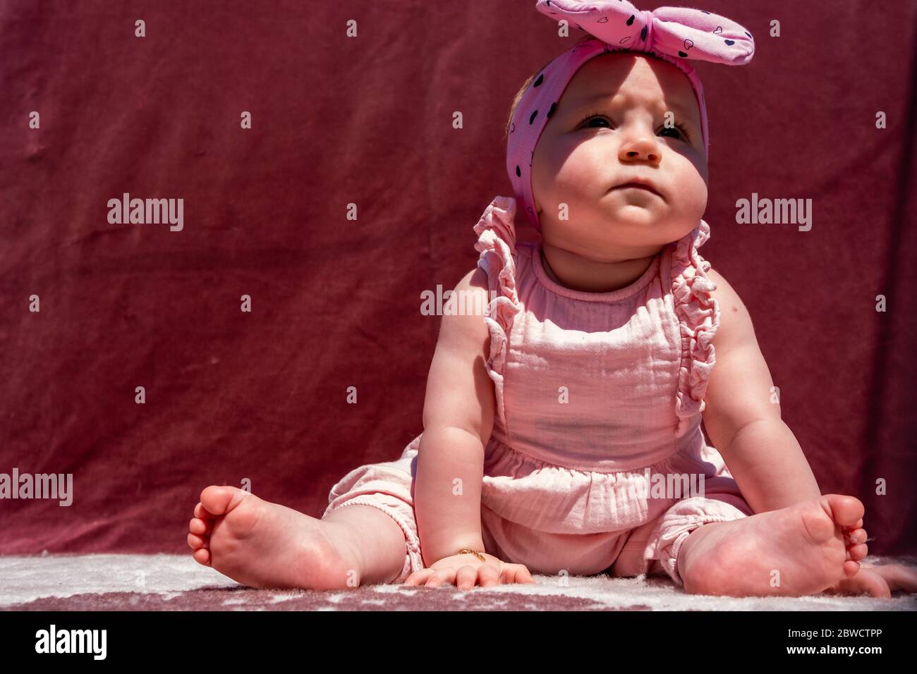 Cute little baby girl wear hat and sit on carpet at outside, looking at camera and smiling Stock Photo