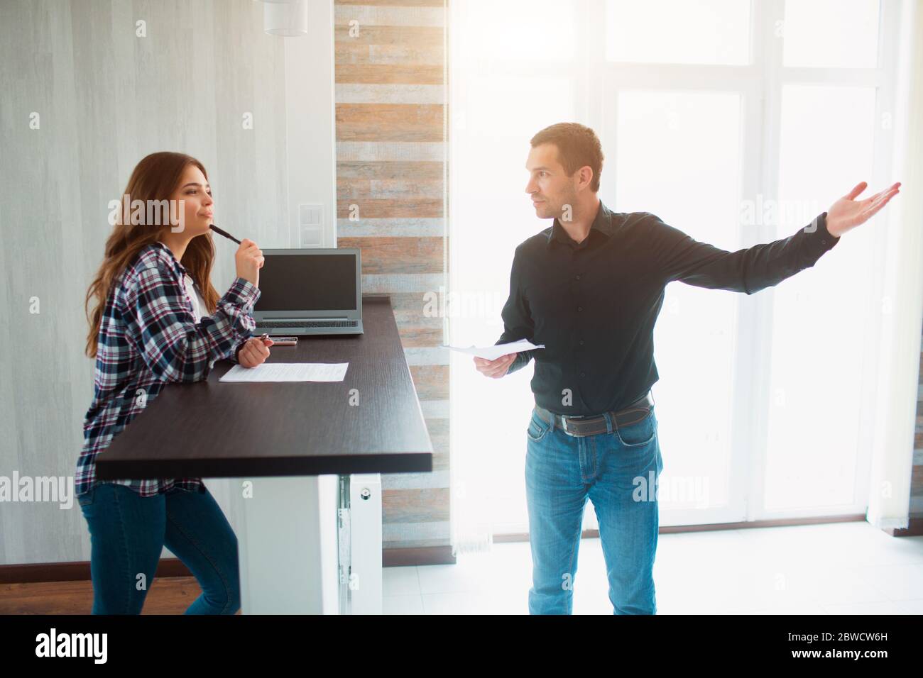 Realtor, broker or landlord shows an apartment to a young woman. She is going to sign a lease agreement with him. Stock Photo