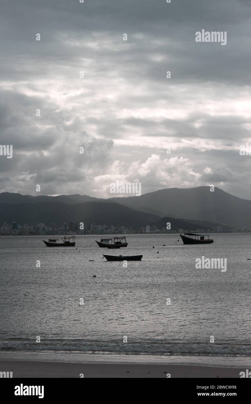 perfectly aligned with the mountains in the background 4 boats are stopped in the middle of the scene with the mountains and city in the background, t Stock Photo