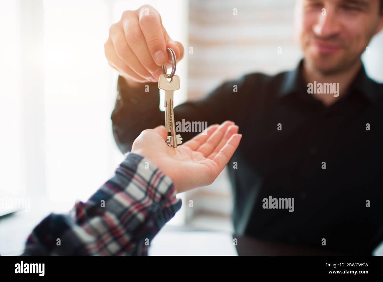 Real estate agent giving key of new house to young woman in office ...