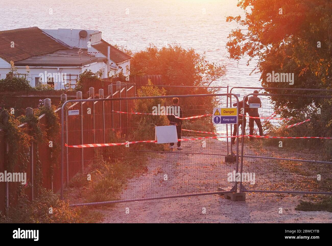 Eastchurch, Kent, UK. 31st May, 2020. Three daredevils were spotted taking a quick look over the collapsed cliff edge in Eastchurch, Kent at sunset this evening - which is at risk of further collapse at any moment -  ignoring three sets of safety barriers put in place by the authorities. Credit: James Bell/Alamy Live News Stock Photo