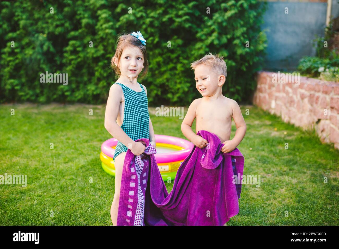 Children wrapped in a beach towel during summer vacation. Wet kids on summer swimming pool with towel. babies having happy time on summer basin. Theme Stock Photo